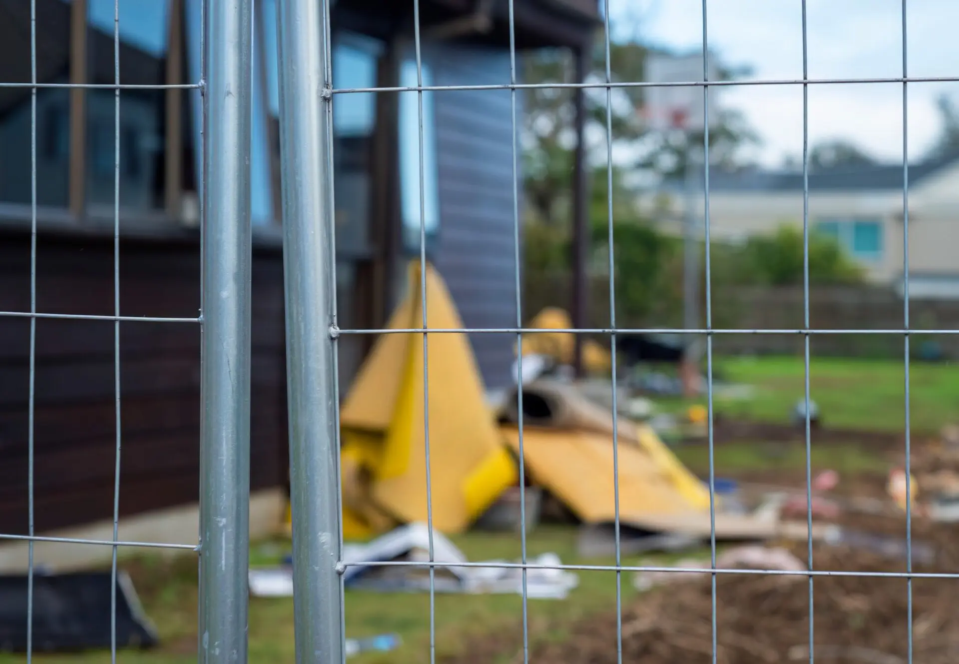 Temporary construction fencing protecting residential property under repair. Selective focus on fence.